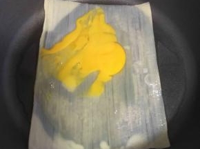 放入一个鸡蛋，用铲子拍开，均匀的涂抹在冷面上