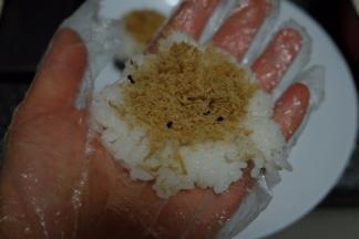 戴上一次性手套，抓一小块米饭在手里按扁，放上一点肉松，这个肉松是我自己做的，想要看做法的可以看我昨天发的贴子；