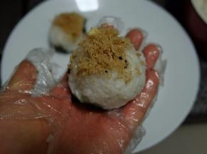 再抓一点米饭，把饭团裹成一个球状；底部托一张海苔，顶部撒上一些肉松就可以了；