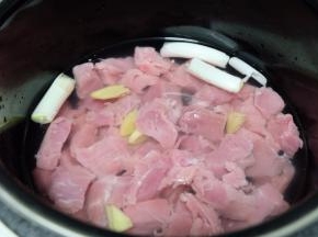 切点葱段和姜片；放进高压锅里，加上水，盖住肉就可以了，倒点白酒，料酒也可以，我家没有料酒了，我放的白酒；