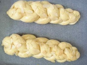 发酵好的面团明显发胖，此时面包表皮刷上蛋液，撒上杏仁片