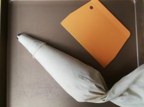 裱花嘴放入裱花袋，将面糊装入裱花袋，建议使用布裱花袋或者硅胶裱花袋，防止面糊爆袋。然后借助刮板使面糊集中在裱花袋内。