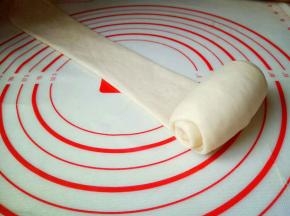 取一块面团，用擀面杖擀长舌状，再卷起来，从上往下卷起来，一次做完。