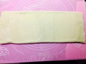 撒手粉，将过好黄油的面饼，擀成长方形。这里值得注意的是，因为面团与黄油温度都比较低，直接擀比较费劲，那么！我们用擀面棍垂直于面饼上方，用干擀面棍垂直向下压它。会并排压出一道一道的凹槽。然后再平均力道擀成长方形即可。