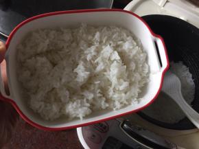 勺入煮好的米饭到烤盘里，米饭用饭勺轻轻打散