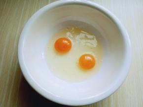 将鸡蛋敲在大口器具中。