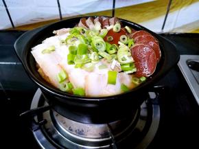 盛出部分煮好的酸菜装满小煲，撒入少许味精，把熟五花肉切薄片，血肠切成小块（忘记拍照了），摆放在酸菜上面，再撒上些许葱花，开火煮十分钟左右。