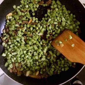 6.倒入豆角丁，并加入适量生抽，盐及十三香继续翻炒，炒制过程中多次少量加入水，直至炒熟收汁