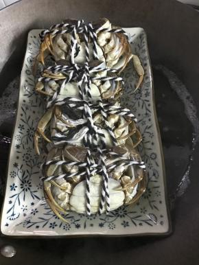 把蟹松绑后用牙刷刷洗干净，我重新用绳子捆扎了一下。锅中放适量水，煮开后在水里加入适量料酒和姜片，蟹肚朝上放入锅中。