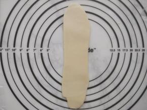 取一个卷好的面团，沿着长方向擀开成长条形。