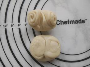 取一个卷好的面团，用筷子在中间轻压一下，两边向中间推压，再用手掌按扁。