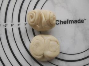 取一个卷好的面团，用筷子在中间轻压一下，两边向中间推压，再用手掌按扁。