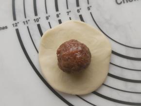 用擀面杖擀开面皮，放上玫瑰馅料，包好并捏紧收口。