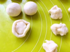 取一份水油皮材料，用手掌压扁，包裹上油酥皮材料，收好收口，之后盖保鲜膜松弛10分钟