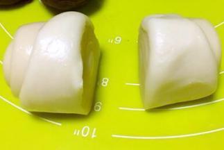 取一份松弛好的面团，用刀从中间切开，分成两等份，切口面朝下，擀成圆片，包裹上莲蓉蛋黄馅，收好收口，之后整理下形状