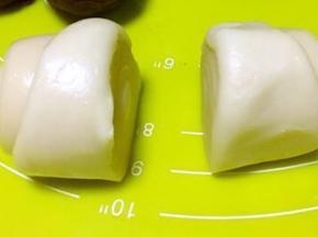 取一份松弛好的面团，用刀从中间切开，分成两等份，切口面朝下，擀成圆片，包裹上莲蓉蛋黄馅，收好收口，之后整理下形状