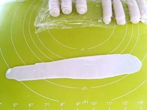 将松弛好的牛舌卷再擀成长条，卷起来，继续盖保鲜膜松弛15分钟