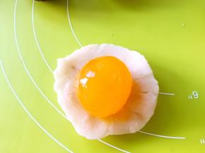 将馅分成9等份，取一份馅总手掌压扁，包裹上咸蛋黄，收好收口