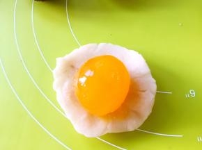 将馅分成9等份，取一份馅总手掌压扁，包裹上咸蛋黄，收好收口