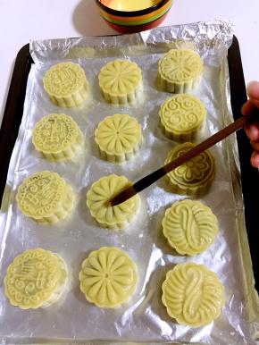 烤五分钟后取出烤盘，细毛刷在碗壁上刮几下，再在月饼表面薄薄的刷一层蛋黄水！不要刷的太多，否则月饼表面的花纹会模糊！