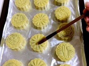 烤五分钟后取出烤盘，细毛刷在碗壁上刮几下，再在月饼表面薄薄的刷一层蛋黄水！不要刷的太多，否则月饼表面的花纹会模糊！