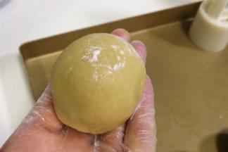 取一个包好馅料的小圆球，搓成圆柱状，表面拍上少许干面粉。