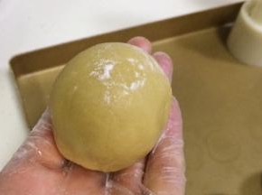 取一个包好馅料的小圆球，搓成圆柱状，表面拍上少许干面粉。