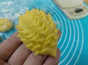 用小剪刀剪出一根根小刺。放在油纸上，在眼睛的位置沾点水粘上芝麻。