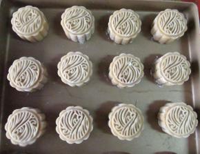 包严实后放入模具成形。模具要先撒糯米粉或者干淀粉放沾，撒好粉再磕出粉，不然粉太多了不好.做好的月饼胚放入烤盘，烤前要喷水