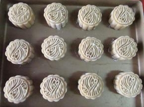 包严实后放入模具成形。模具要先撒糯米粉或者干淀粉放沾，撒好粉再磕出粉，不然粉太多了不好.做好的月饼胚放入烤盘，烤前要喷水