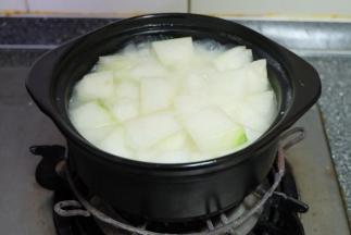 这个时候，砂锅的米饭表面冒大泡了，把切好的冬瓜块放进砂锅；继续小火焖煮；