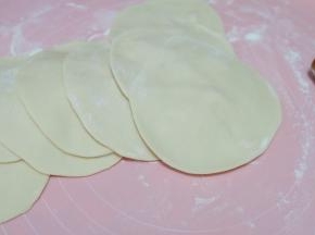 把清水和酵母粉先放进小盆里混合均匀，再把面粉放进去，混合均匀后放置揉面垫上，揉成一个光滑的面团，再分成若干个小面团，揉圆后擀开，擀成四周薄，中间厚的圆面片，就是包子皮了。我这里用的是一次发酵法。