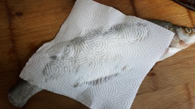 2.把鱼的水分空掉，放在案板上，用厨房纸吸去多余的水。