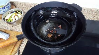 11.铁锅中放入适量的花生油（油比平时炒菜时略多），花椒与八角放入油中一起加热。