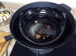 11.铁锅中放入适量的花生油（油比平时炒菜时略多），花椒与八角放入油中一起加热。