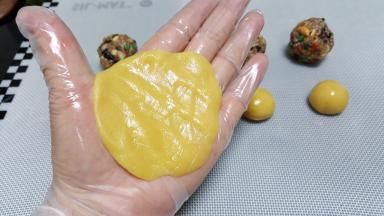 5．取一份饼皮，用手把它压扁，压成能包裹住馅料大小的圆皮。