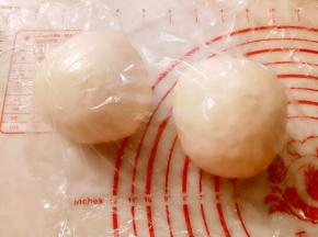 取出面团排气后，平均分成2份，滚圆盖保鲜膜松弛20分钟。