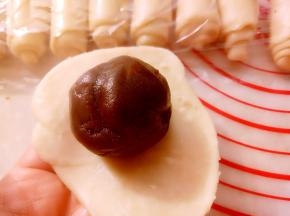 用擀面杖擀成圆形放入之前准备好的豆沙蛋黄馅包好。