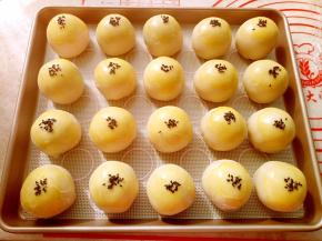 包好的蛋黄酥收口朝下，整齐地摆放在阳晨12寸浅烤盘里。表面刷上蛋黄液点缀上黑芝麻。