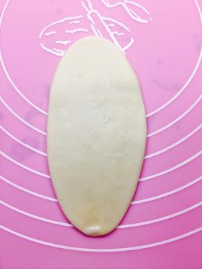 放置后，将包好油酥的小面团，按扁。擀成牛舌型。不要太用力，也不用擀的特别长。