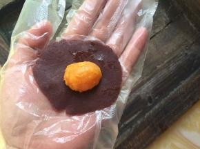 然后将红豆沙按扁，中间厚边缘薄，放入咸蛋黄
