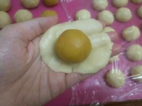 取一块饼皮擀开，包入一个蛋黄豆沙馅。