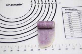 将擀好的油酥面团由上往下卷起。