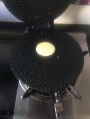 用调羹舀一勺面糊放在已预热的蛋卷模具靠前面的地方，煤气灶开小火，做第一个时要多等下