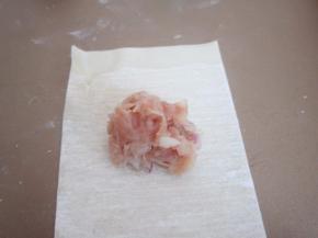 取一张馄饨皮，放上肉馅。在皮的上方涮点清水。