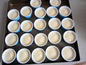 把拌好的蛋糕糊倒到裱花袋，挤入蛋糕杯中（7分满）。全部挤完后提起烤盘震两下，把大的气泡震出来！