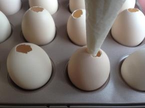 将蛋糕糊挤进蛋壳里，装5、6分满可以了。蛋壳可以架在12连小蛋糕模里，是刚刚好的