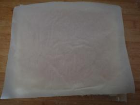 再取一张干净的油纸，盖上蛋糕，将蛋糕有提子的一面向下。