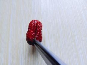 首先将大枣冷水冲洗干净，再用食品剪刀从大枣中间剪开，底部不要剪开，如图。