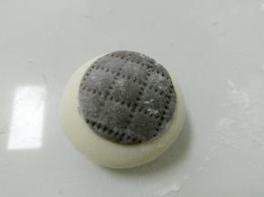 白面团搓圆，然后贴上黑色圆面片。再用干净的梳子，压出印痕，也可以用刀背。